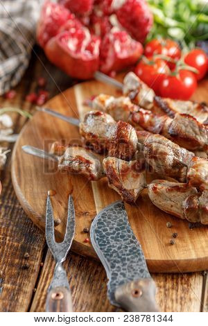 Tasty And Juicy Kebabs Of Pork On A Wooden Board With Original Cutlery.