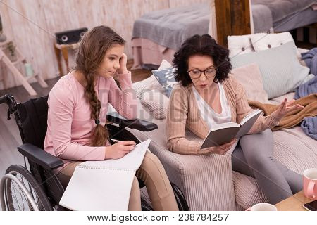 Difficult Assignment. Pretty Handicapped Girl Writing While Woman Declaiming