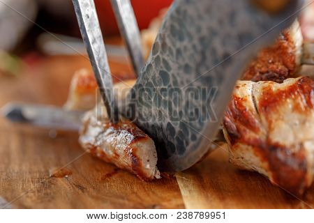 Delicious And Juicy Kebabs Of Pork On A Wooden Board That Are Cut With Original Cutlery For Meat.