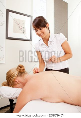 Nainen acupuncturist performing takaisin hoitoa naisten pasient.