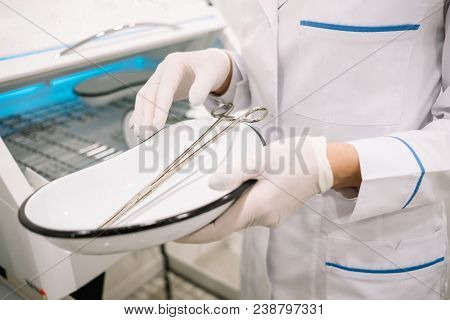 Hand Of Doctor In Medical Glove With Medical Arterial Clamp