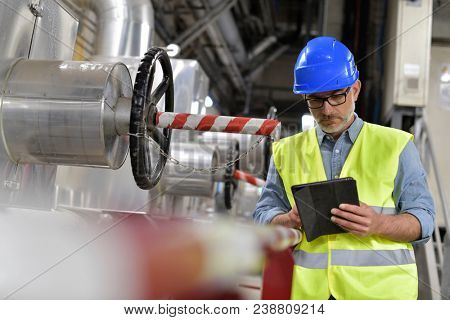 Industrial technician connected with tablet in recyling plant