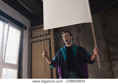 Bottom View Of Angry Shouting Young Man In Vintage Windcheater With Blank Placard