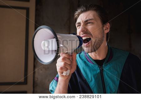 Mad Young Man In Vintage Windcheater Shouting With Loudspeaker