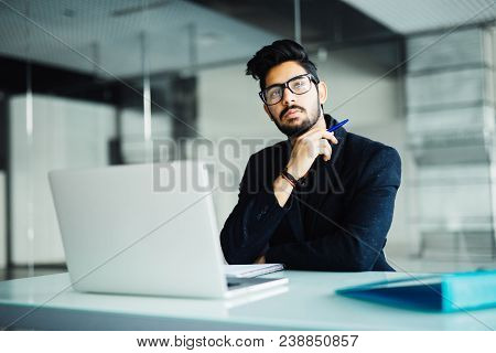 Business And People Concept. Indian Businessman With Papers And Laptop Computer Working At Office