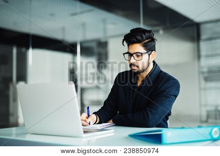Business And People Concept. Indian Businessman With Papers And Laptop Computer Working At Office