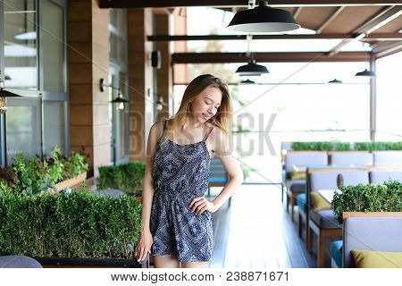 Pretty Woman Standing At Cafe Near Green Palnts. Concept Of Resting At Break Time And Youth.