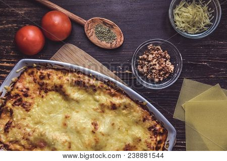 Lasagne Layered Served On A Wooden Board With Fresh Tomatoes Alongside Cheese