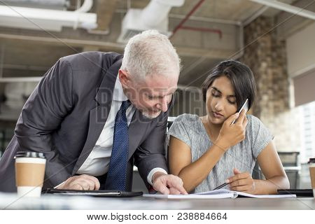 Focused Business Leader Supervising Managers Work. Young Indian Woman Speaking On Phone At Workplace