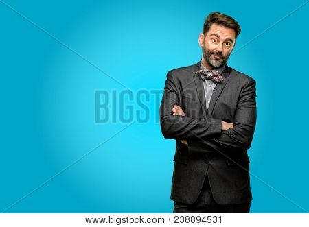 Middle age man, with beard and bow tie with crossed arms confident and happy with a big natural smile laughing