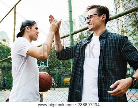 Young adult male friends playing basketball in the park
