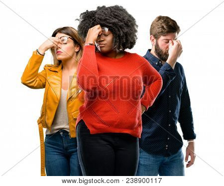 Group of three young men and women with sleepy expression, being overworked and tired, rubbes nose because of weariness