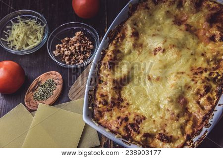 Lasagne Layered Served On A Wooden Board With Fresh Tomatoes Alongside Cheese