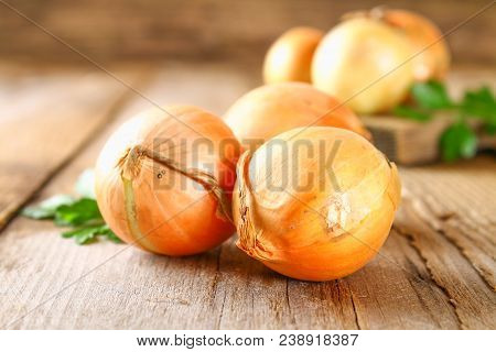 Yellow Onion With Parsley On A Wooden Table
