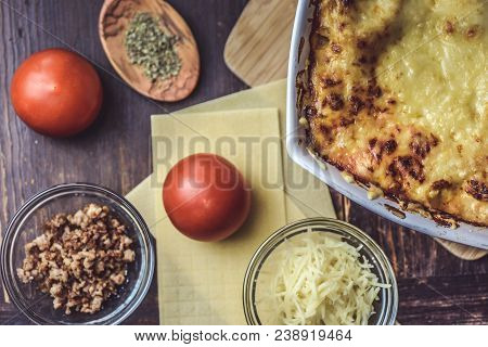 Lasagne Layered Served On A Wooden Board With Fresh Tomatoes Alongside Cheese