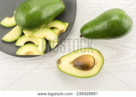 Green Smooth Avocado Sliced Composition On A Grey Plate Table Top Isolated On Light Wood Background 