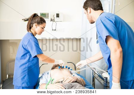 Two Doctors Placing Ecg Electrodes On The Chest Of Patient In Emergency Room