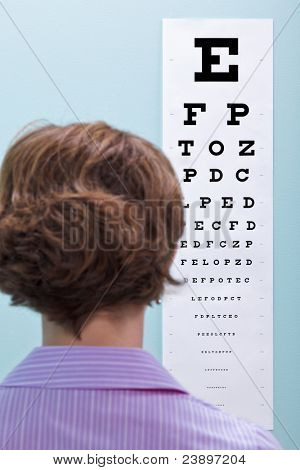 Foto einer Frau auf die Optiker haben ihr Sehvermögen mit einem Auge-Diagramm um zu sehen, ob sie g braucht getestet