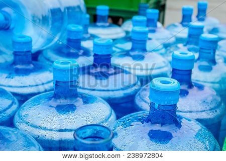 Big Empty Plastic Water Bottles For The Cooler Are Stacked At Outdoor Warehouse.