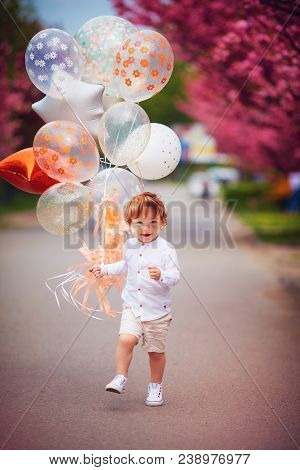 Happy Toddler Boy Running The Spring Street With The Bunch Of Air Balloons