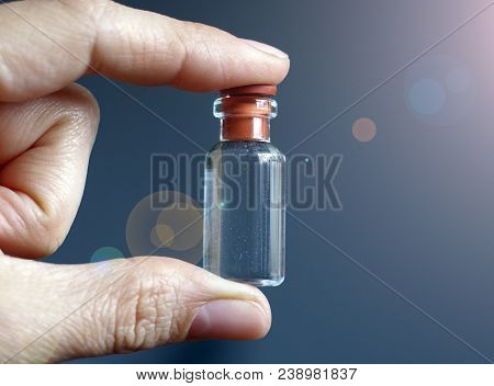 Hand Of A Man With A Small Bottle Of Elixir In The Sunlight Glare