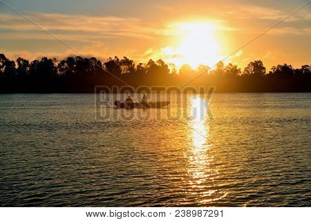 Sunrise On The River. A Boat With Anglers. Beautiful Reflexes On The Water.
