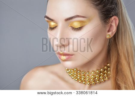 Portrait Of A Beautiful Happy Woman With Beautiful Creative Makeup In Gold Colors. She Has Gold Bead