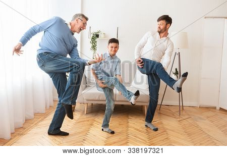 Happy Grandfather With Mature Son And Grandson Having Fun Pretending To Play A Guitar At Home. Multi