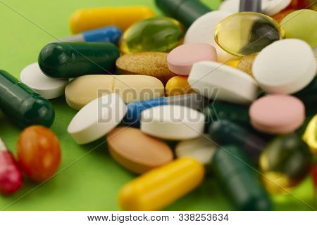 Group Of Bright Multi-colored Pills On A Green Background. Cropped Shot, Horizontal, Side View. The 