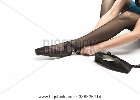 Closeup Of Legs Of Female Ballet Dancer Making Up Pointes Shoes With Laces. Horizontal Image