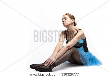 Portrait Of Dreaming Caucasian Ballet Dancer In Blue Tutu And Pointes Shoes Posing Against White Bac