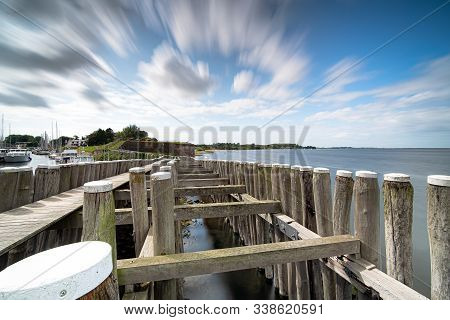 Dynamic Moving Exaggerated White Clouds Against A Blue Sky Above A Dutch Lake Near An Old Seaport