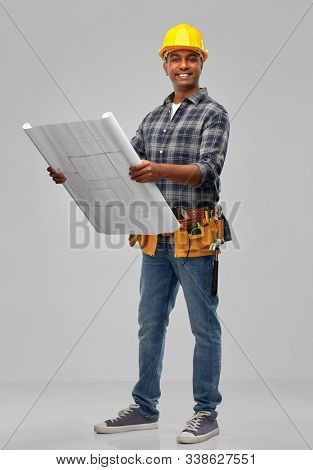 profession, construction and building - happy smiling indian builder in helmet with blueprint over grey background