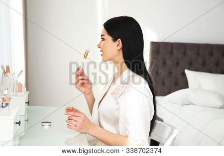 Beautiful Young Woman In Robe Doing Make Up At Dressing Table Indoors