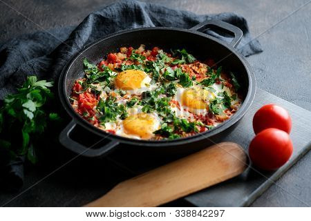 Traditional  Shakshuka With Eggs, Tomato, And Parsley In A Iron Pan On A Dark Background