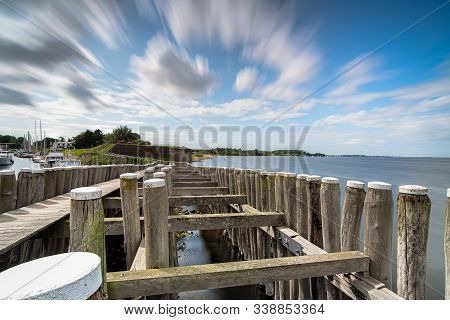 Dynamic Moving Exaggerated White Clouds Against A Blue Sky Above A Dutch Lake Near An Old Seaport