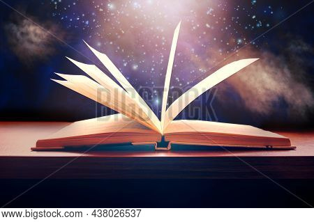 Old Opened Book On Table With Magic Smoke, Light And Falling Stars Overlay On Background. Book With 