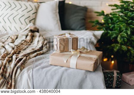 Wrapped Christmas Presents On Cozy Bed Next To Christmas Tree With Beautiful Blurred Lights On The B