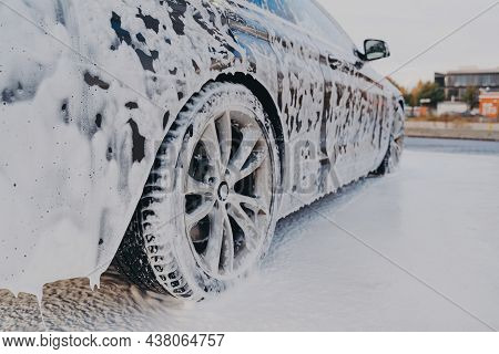 Vehicle Covered In White Soapy Foam During Regular Carwash Outdoors, Auto Getting Professional Wash 