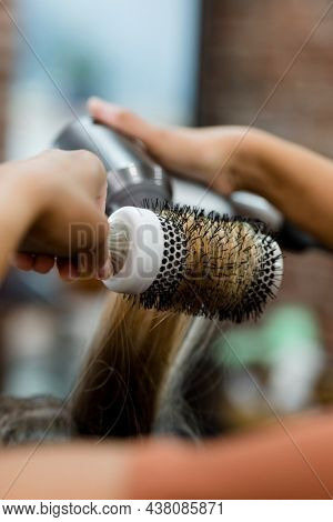 Hairstylist blow drying the customer hair