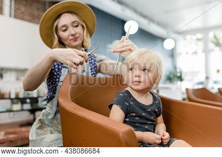 Hairstylist giving a haircut to an adorable blond kid
