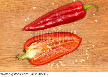 Half Of The Fresh Bell Pepper Orange Color Cut Lengthwise And Whole Red Pod Lie On The Wooden Cuttin