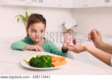 Mother Feeding Her Daughter In Kitchen, Closeup. Little Girl Refusing To Eat Vegetables