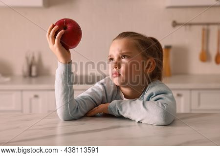 Cute Little Girl Refusing To Eat Apple In Kitchen
