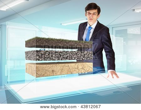 Image of young businessman looking at high-tech picture of topsoil