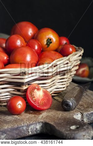 Fresh Red Tomatoes In Whicker Basket On Black Background.