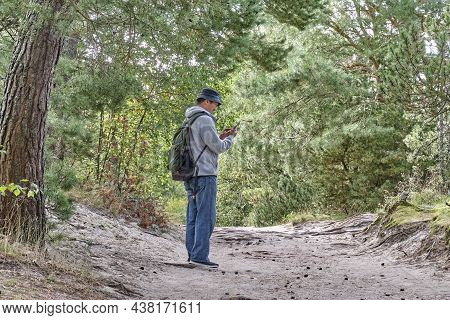 Mature Man In Panama Hat, In Blue Jeans And Gray Sweatshirt, With Backpack Standing On Tourist Trail