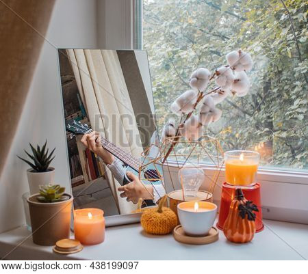 Girl Sits In Her Room On A Window Sill Decorated For The Holiday And Plays The Ukulele. Her Reflecti