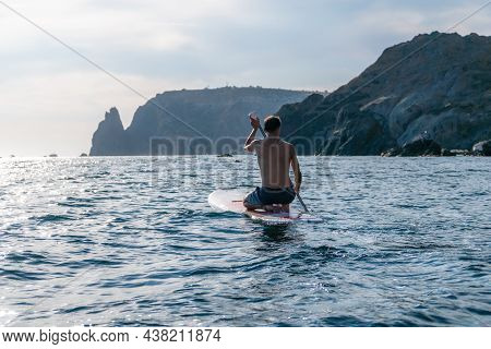 Side View Foto Of A Man Swiming And Relaxing On The Sup Board. Sportive Man In The Sea On The Stand 
