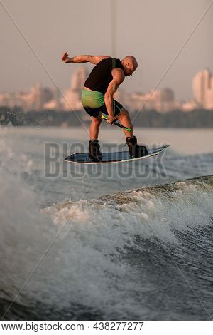 Great View Of A Muscular Man With A Wakeboard While Jumping Over The Wave